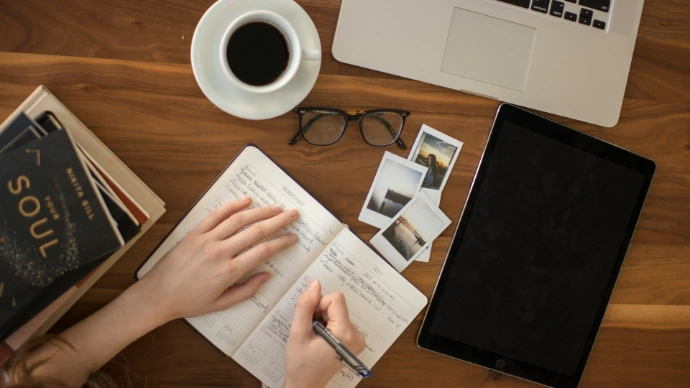 person holding ballpoint pen writing on notebook